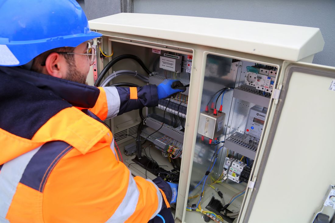 Electrician with a clipboard and flashlight assessing an electrical system in a utility area